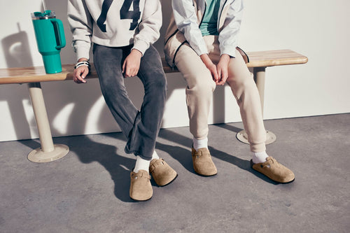Two children sitting on a bench wearing Birkenstock Boston Clogs