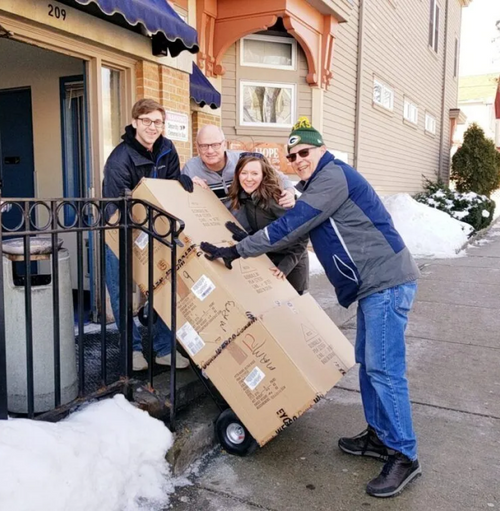 Group of people posing next to three boxes of shoes for donation